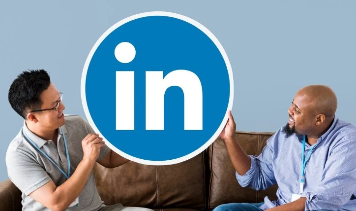 imagem mostra dois homensa sorridentes olhando para a logo do linkedin. eles ilustram o artigo, agência de linkedin ads em São Paulo